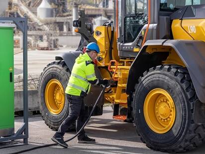 Förare som laddar en stor eldriven Volvo L90 hjullastare.