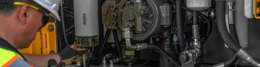 Close up of a service technician working on a machine, with a “Keep Your Volvo Running Like A Volvo” text overlay.